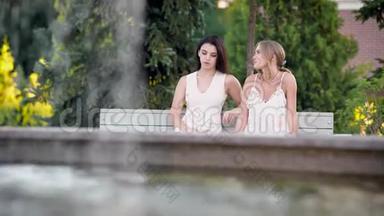 吸引人的朋友在<strong>公园里</strong>谈论夏天的生活，女孩们<strong>坐在</strong>喷泉附近的<strong>公园里</strong>。